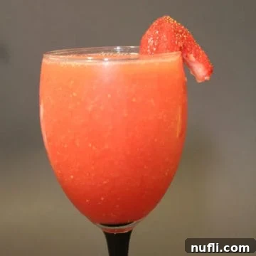 Coral Reef cocktail with a strawberry garnish in a champagne glass