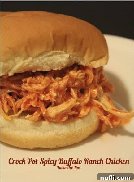 Close-up of shredded Crock Pot Spicy Buffalo Ranch Chicken on a toasted bun with pickles