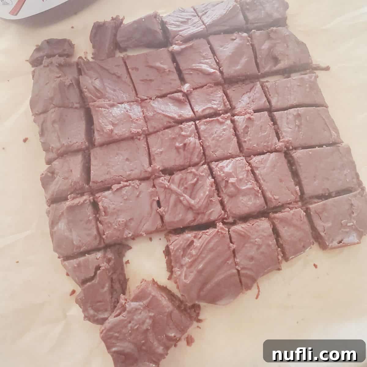 Squares of rich 2-ingredient Nutella fudge resting on parchment paper, ready to be enjoyed.