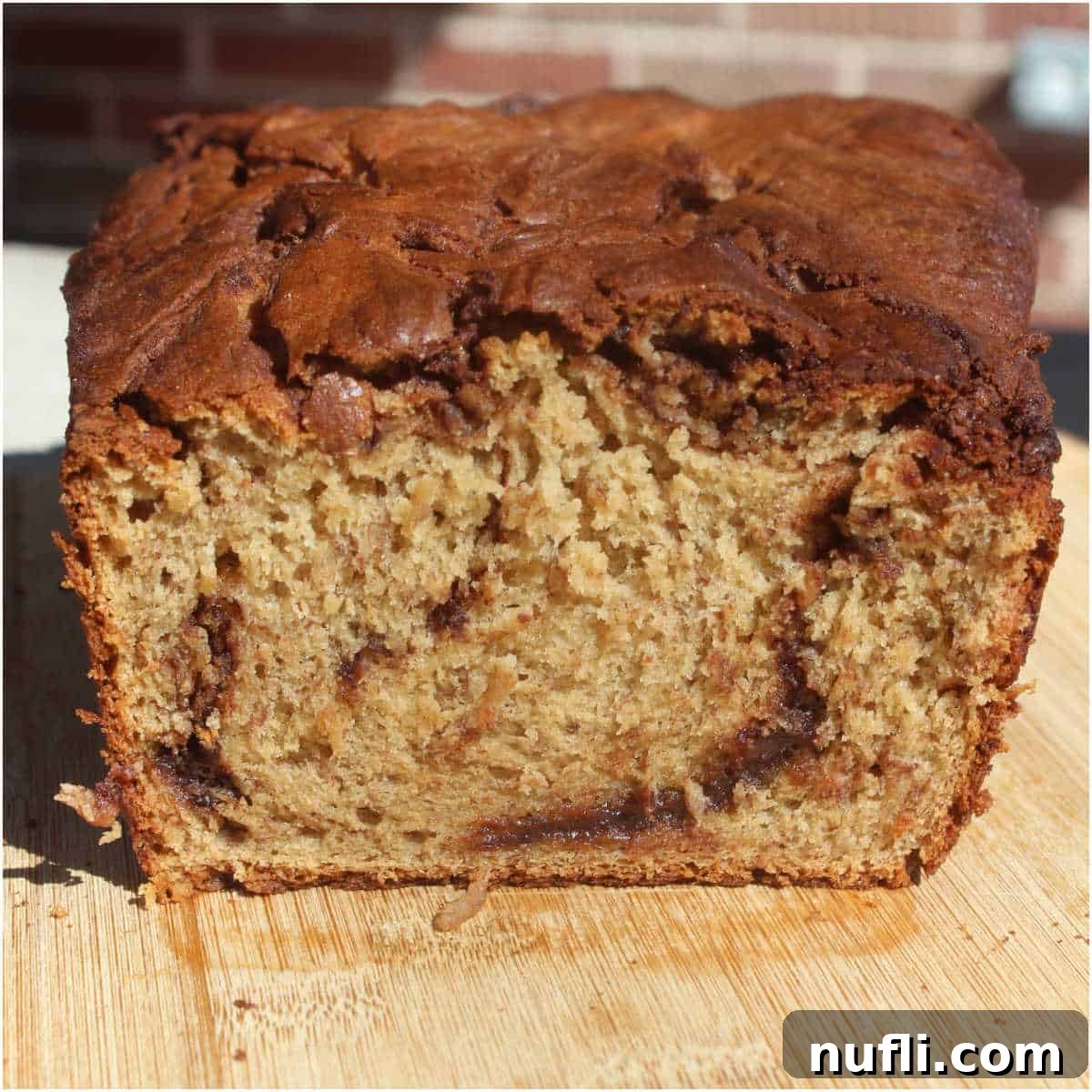 A freshly baked loaf of Nutella Banana Bread, sliced and presented on a rustic wooden board, ready to be served.
