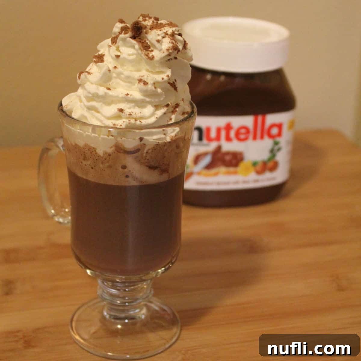 Nutella hot chocolate topped with whipped cream in front of a nutella container