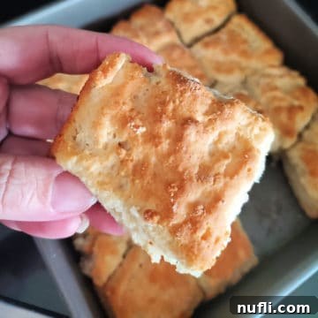 A 7 Up biscuit being held above a pan of biscuits, illustrating the recipe