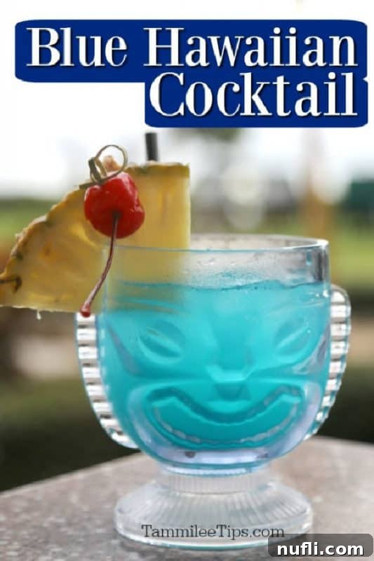 Blue Hawaiian Cocktail over a tiki glass with a blue drink, pineapple cherry garnish