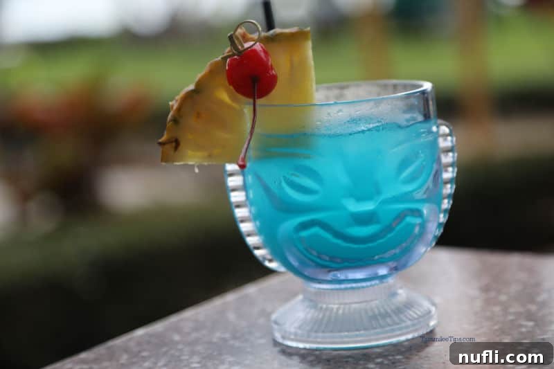 Tiki glass with a blue drink, pineapple cherry garnish, with a tropical background