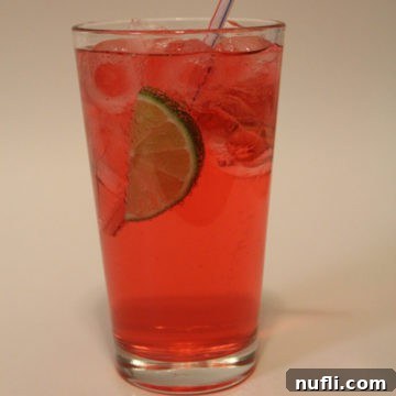 cherry limeade in a tall glass with a lime wedge and straw