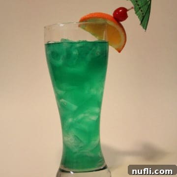 Bright green Chili's Jamaican Paradise cocktail in a tall glass with orange slice and cherry garnish