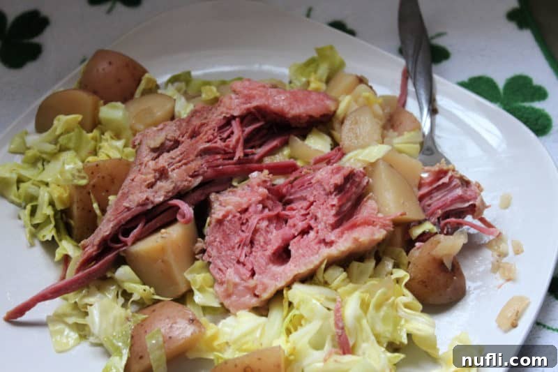 Corned Beef Cabbage and Potatoes on a white plate with a fork. 