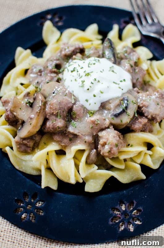 Easy Crock Pot Beef Stroganoff with a sour cream garnish on a blue plate
