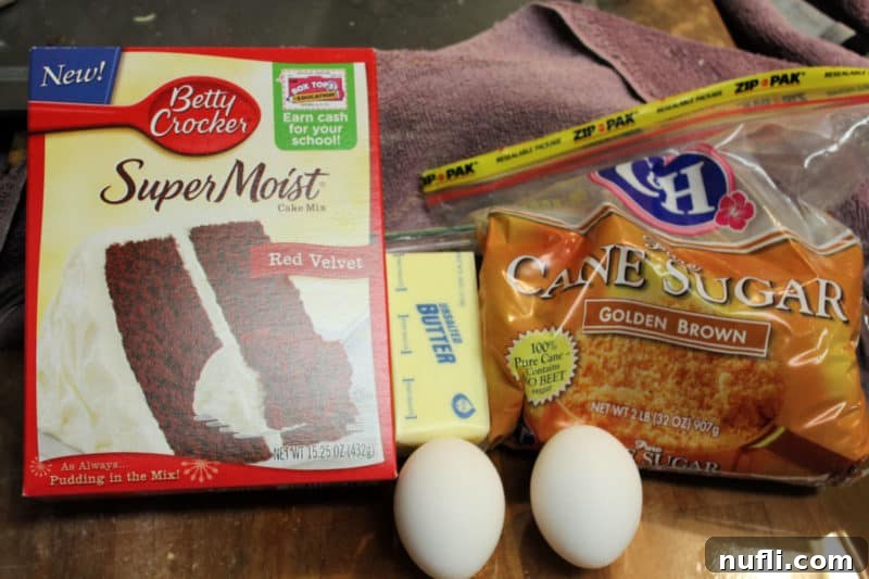 Red Velvet cake mix, eggs, butter, and brown sugar laid out on a kitchen counter, ready for mixing.