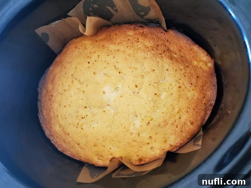 Cornbread baking in a slow cooker bowl lined with parchment paper