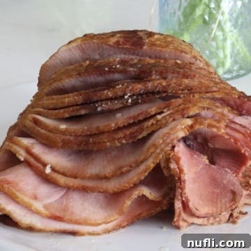 Close up of spiral ham next to a vase on a white platter