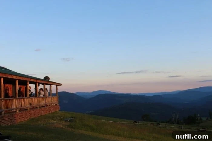Serene outdoor deck overlooking expansive rolling hills bathed in the warm glow of a sunset at Bull Hill Guest Ranch, offering a perfect spot for relaxation.