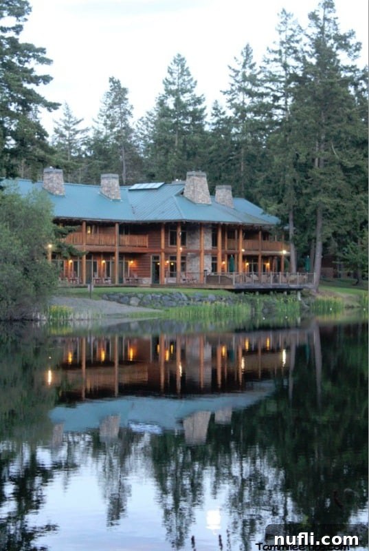 Your Log Cabin Adventure Awaits at Lakedale Resort, San Juan Islands 9 Lakedale resort buildings beautifully reflecting on the tranquil lake surface, surrounded by lush trees under a clear sky.