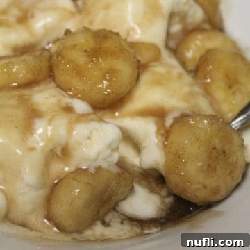 Effortless Slow Cooker Bananas Foster Dessert 3 Crock Pot Bananas Foster in a white bowl with vanilla ice cream and an extra banana slice.