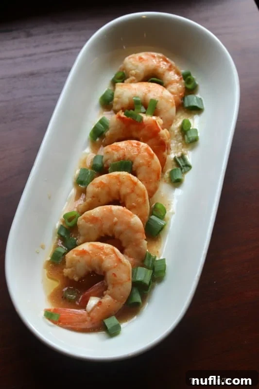 New Orleans Slow Cooker Fiery Barbecue Shrimp 3 Spicy BBQ shrimp on a white platter with green onions