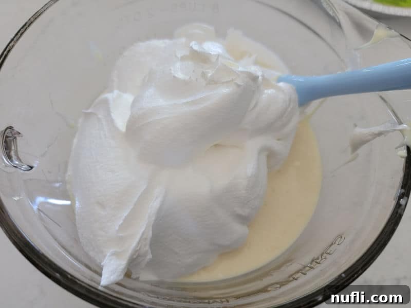 Sunshine Lemon Icebox Pie 6 Cool whip on lemon pie mix in a glass bowl with a spatula