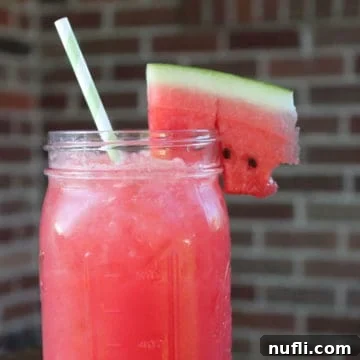 Watermelon Agua Fresca in a mason jar with a watermelon slice, ready to be enjoyed.