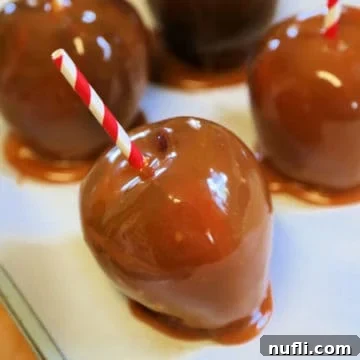 Crockpot Caramel Apples on parchment paper with red striped paper straws