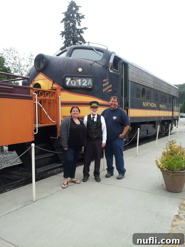 Tammilee and John posing with a friendly train conductor in front of a Northern Pacific train engine.