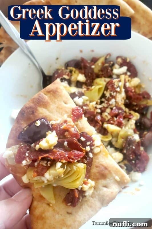 Heavenly Greek Goddess Bites 2 A close-up of a Greek Goddess Appetizer, featuring crumbled feta, chopped kalamata olives, sun-dried tomatoes, and artichoke hearts, served with pita bread.