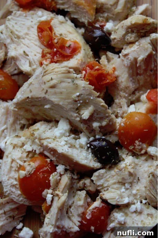 Close up of cooked Greek chicken with tomatoes and Kalamata olives, ready to be tossed with feta.