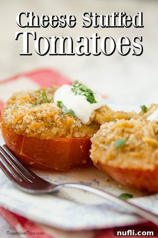 A white plate with a silver fork, featuring a cheese-stuffed tomato topped with sour cream and fresh herbs (basil/parsley).