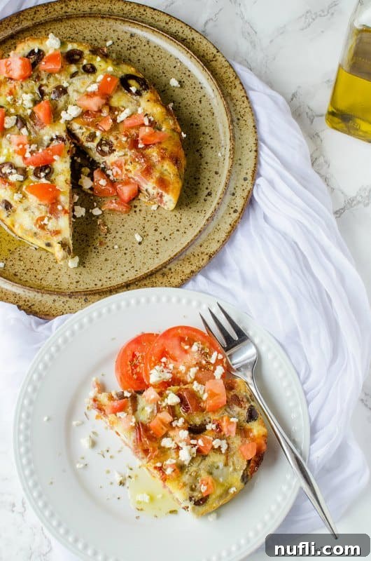 plate with a slice of Greek frittata and tomatoes, next to serving dish.