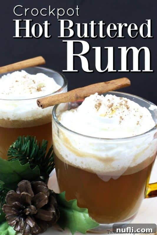 Crockpot Hot Buttered Rum over two mugs garnished with whipped cream and a cinnamon stick