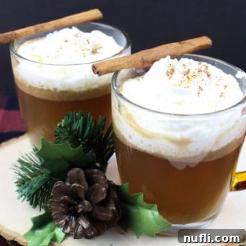 Hot Buttered Rum in glass coffee mugs with cinnamon sticks on a wood board