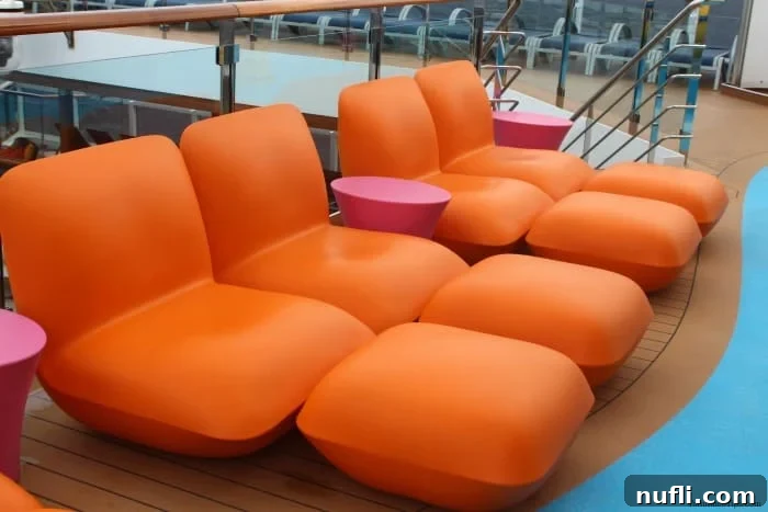 Carnival Waterworks: Your Ultimate Summer Splash 4 Comfortable orange plastic chairs with red side tables, strategically placed for relaxation and supervision near the Waterworks area on a cruise ship.