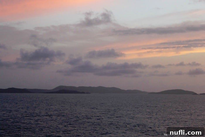 Pink and purple sunset over the glistening ocean, viewed from a cruise ship balcony