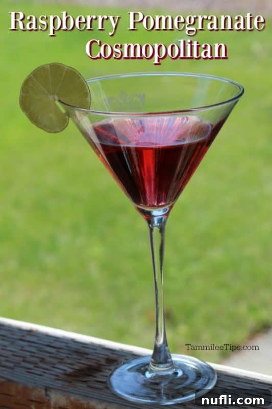 Raspberry Pomegranate Cosmopolitan 2 A vibrant Raspberry Pomegranate Cosmopolitan cocktail in a sleek martini glass, elegantly garnished with a fresh lime wheel, set against a softly blurred background.