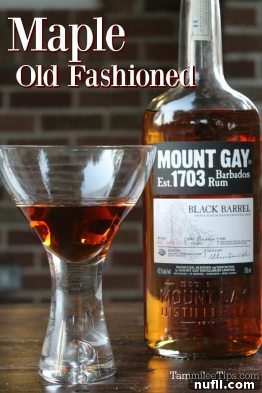 Elevated Maple Old Fashioned Recipe 2 A stunning Maple Old Fashioned cocktail in a martini glass, elegantly placed next to a bottle of Mount Gay Black Barrel Rum, hinting at a luxurious drinking experience.