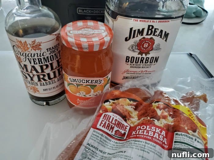 Ingredients for Bourbon Glazed Kielbasa: maple syrup, apricot preserves, bourbon, and sliced Polish Kielbasa in front of a slow cooker.