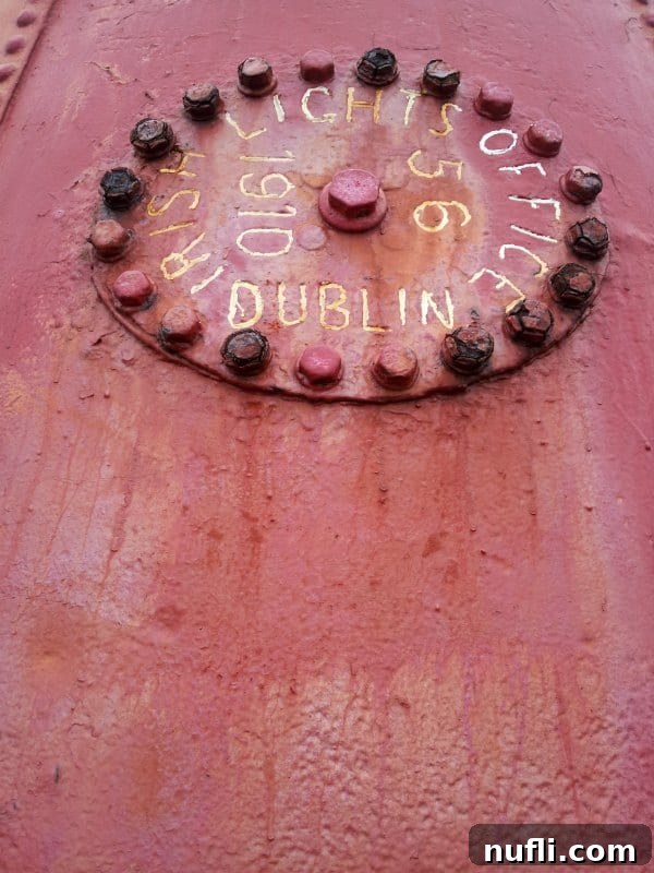 A close-up of a vintage sign inside Hook Lighthouse that reads 'Irish Lighthouse Office Dublin 1910' on a red-painted section.