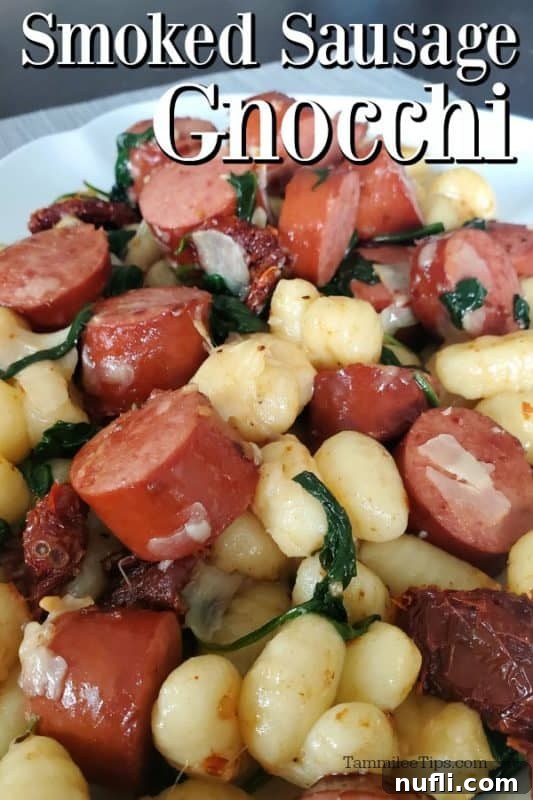 A serving of Smoked Sausage Gnocchi with vibrant sun-dried tomatoes, fresh spinach, and grated Parmesan cheese on a white plate, ready to be enjoyed.