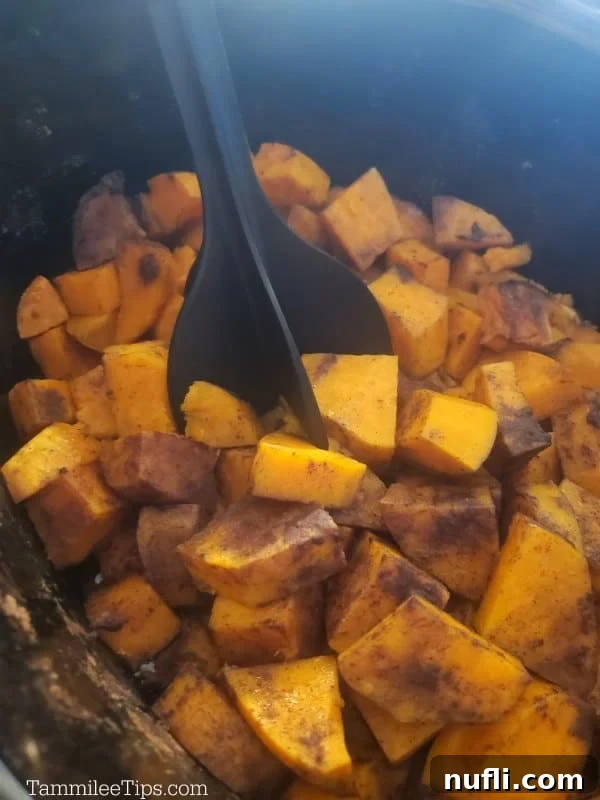 Using a Mix N Chop tool to mash cooked sweet potatoes directly in the slow cooker for convenience.