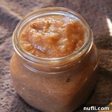 Crockpot pear butter in a glass mason jar on a brown napkin