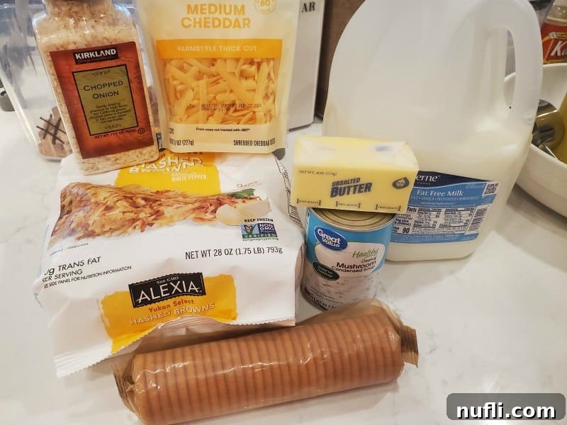 Creamy Slow Cooker Hashbrown Casserole 3 Ingredients for crockpot cheesy hashbrowns laid out: chopped onion, shredded cheddar cheese, milk, frozen hashbrowns, butter, cheese crackers, and cream of mushroom soup.