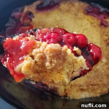 Cherry Dump Cake on a spoon above the slow cooker