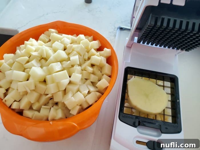 Close-up of potato pieces in an orange bowl next to a potato cutter, ready for slow cooking.