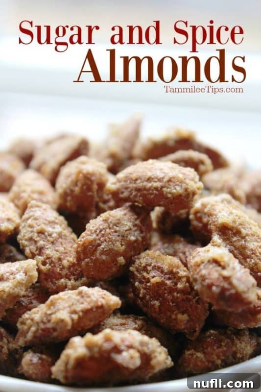 A close-up shot of homemade Sugar and Spice Almonds overflowing from a rustic white bowl, highlighting their glistening, spiced coating.