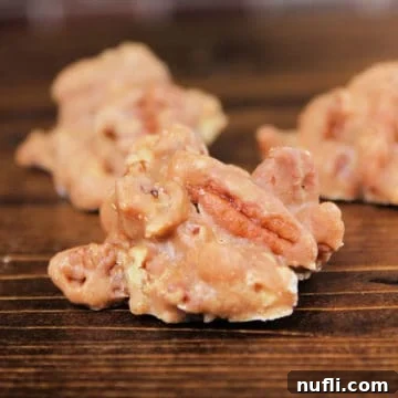 Bourbon Praline Pecans on a wood board, showcasing their glossy, inviting texture.