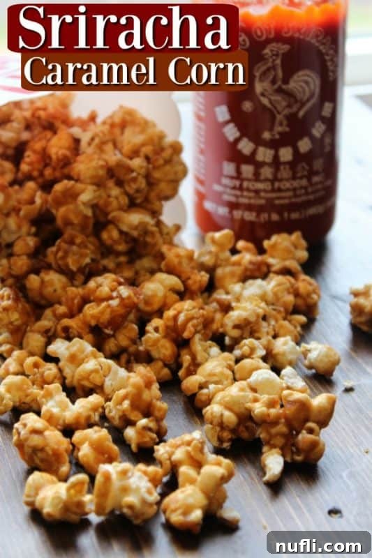 Sriracha caramel corn over caramel corn on a cutting board next to a bottle of sriracha