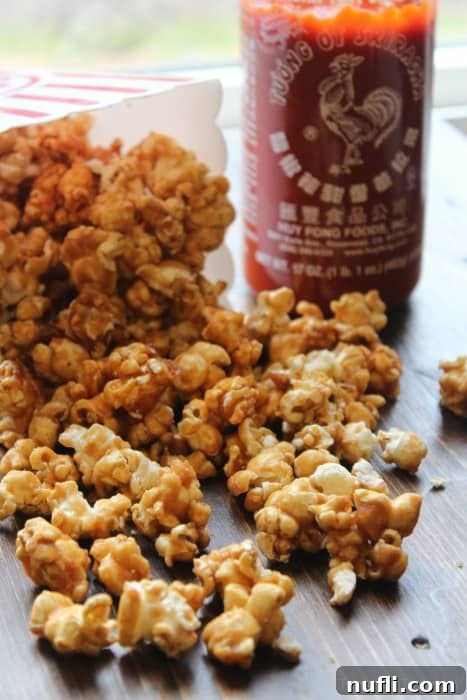 Sriracha caramel corn next to a bottle of Sriracha