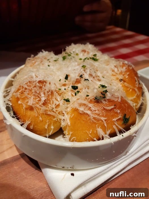 Carnival Cruise Line's Cucina Del Capitano 3 White bowl with freshly baked bread rolls covered in shredded parmesan, a signature appetizer at Cucina Del Capitano
