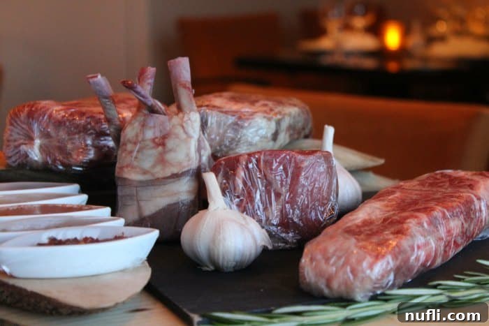 Various cuts of raw steak meticulously wrapped and placed next to bowls of salt and seasonings, ready for preparation
