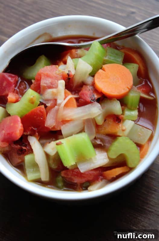 Weight Watchers Vegetable Soup in a white bowl with a spoon on a wood board. 