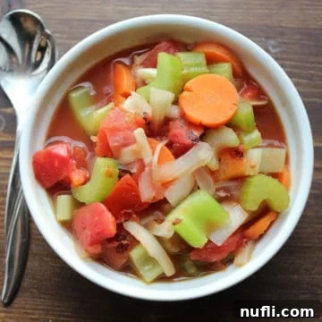 Hearty Weight Watchers Vegetable Soup 4 WW Vegetable Soup with carrots, celery, onions, tomato, in a white bowl next to a spoon