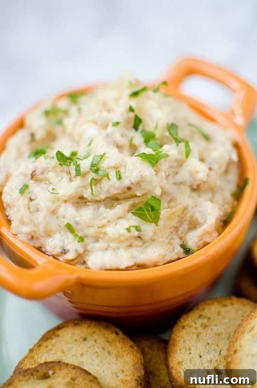 onion dip in an orange bowl with baguette slices next to it